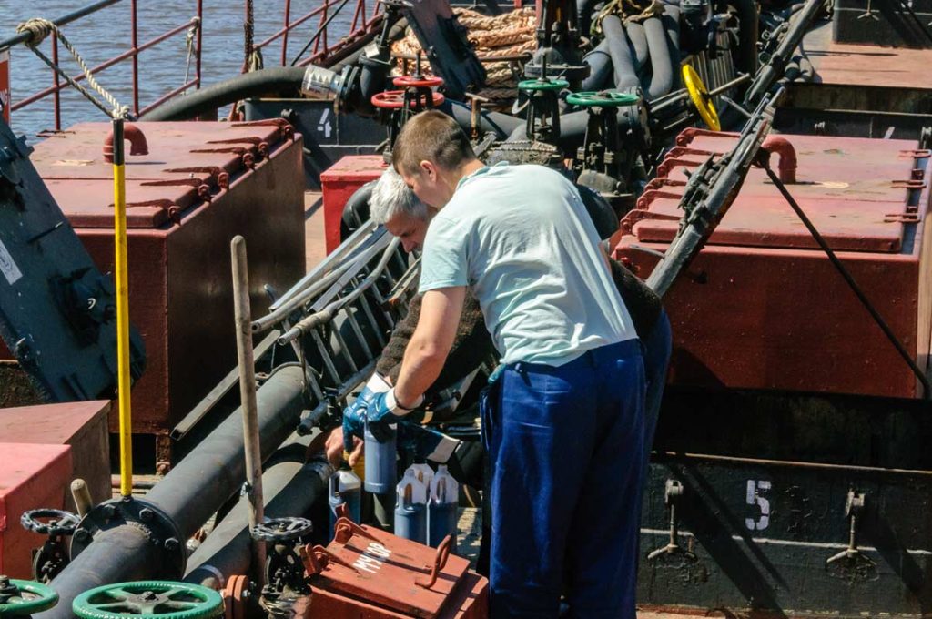 Two men working on the deck of an oil tanker at sea