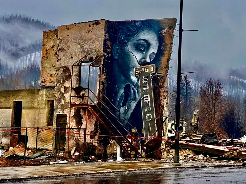 A burned building with a mural on the side in the wake of a California wildfire