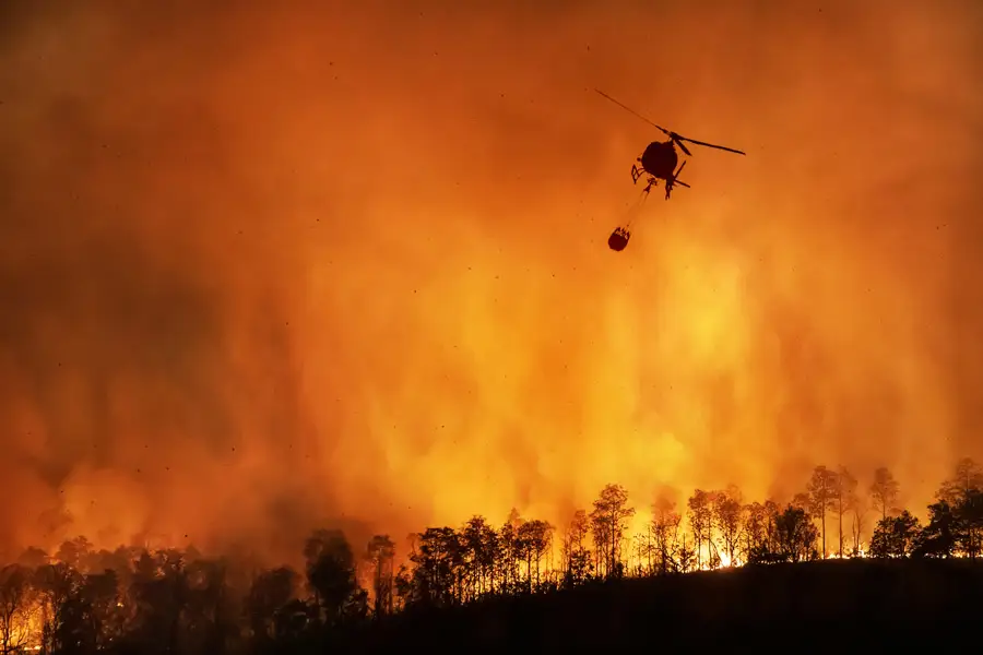 A fire-fighting helicopter with a water bucket over a California wildfire