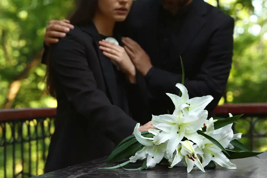 A funeral ceremony with white flowers on a grave