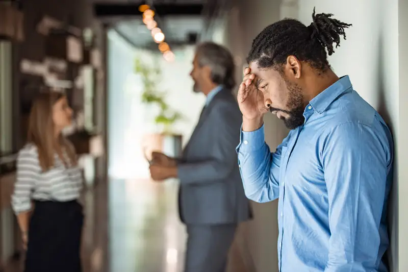 A male office worker looking upset and depressed in the office