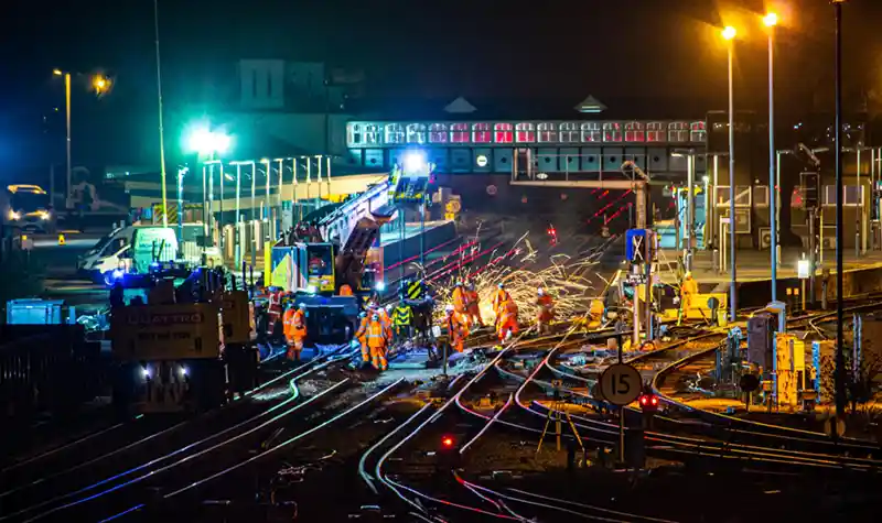 A group of railway workers working on a railroad track at night