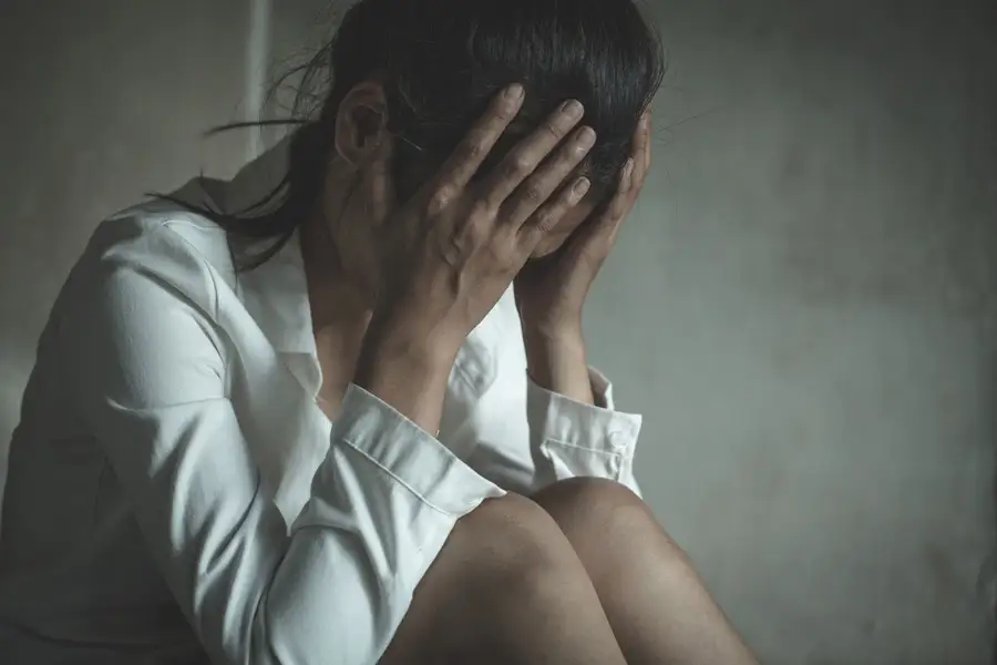 A depressed looking young woman covering her face