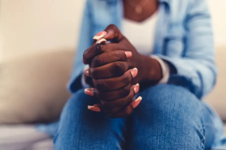 A woman holding her hands together feeling depressed