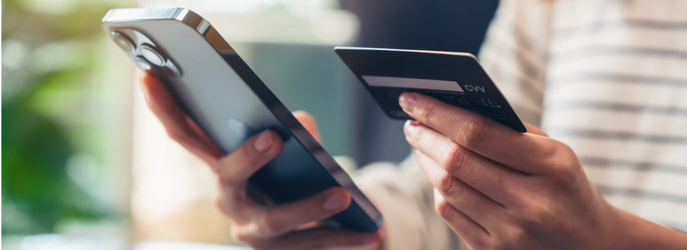 A woman with a cellphone and a credit card
