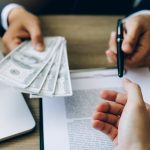 Partner has made a fraud in the contract of sale and being handed a cash and pen to the businessman signing the contract corruption bribery concept.
