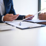 Sales manager giving advice application form document, considering mortgage loan offer for car and house insurance