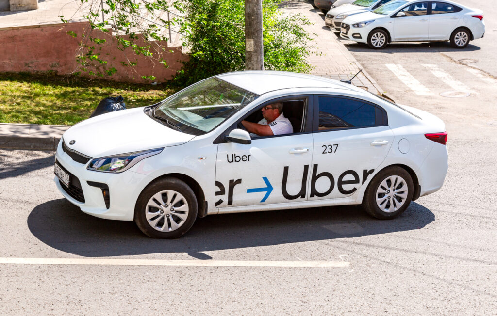 Uber taxi goes down the street in the afternoon. Modern city taxi