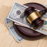 us money with wooden judges hammer on table, top view