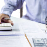 Men's hand holding car key calculate monthly installments and reviewing personal loan contract and car accident insurance before making an agreement about contract to apply for a car loan